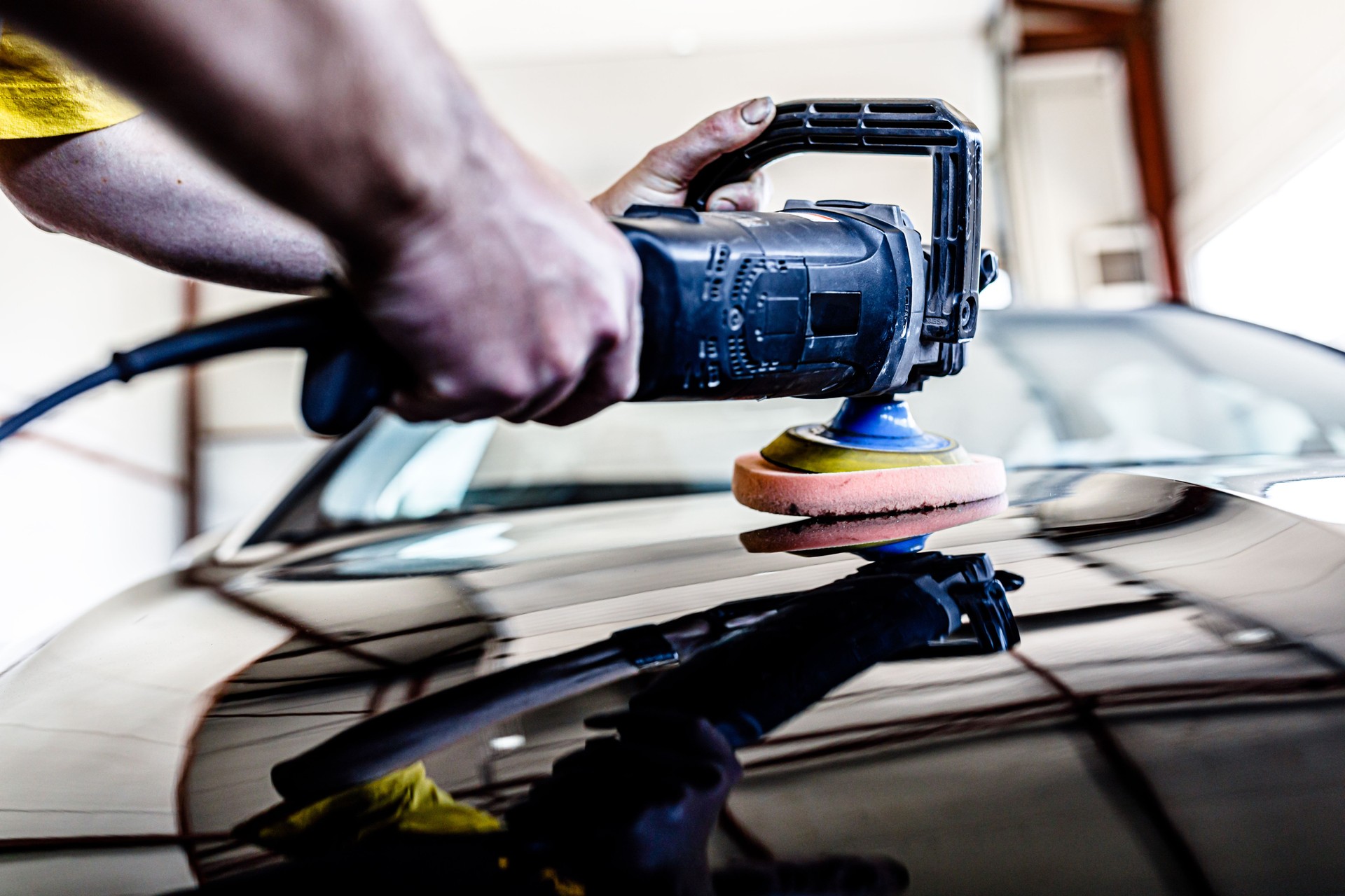 An Experienced Car Mechanic is Polishing a Car in a Car Service.